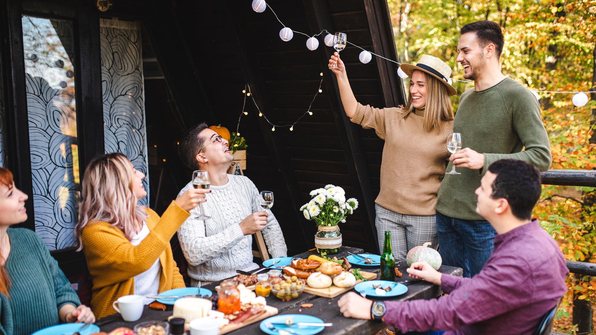 Lovely party hosts leading a speech and toastfor  how grateful they are for this amazing group of people during their reunion over autumn lunch