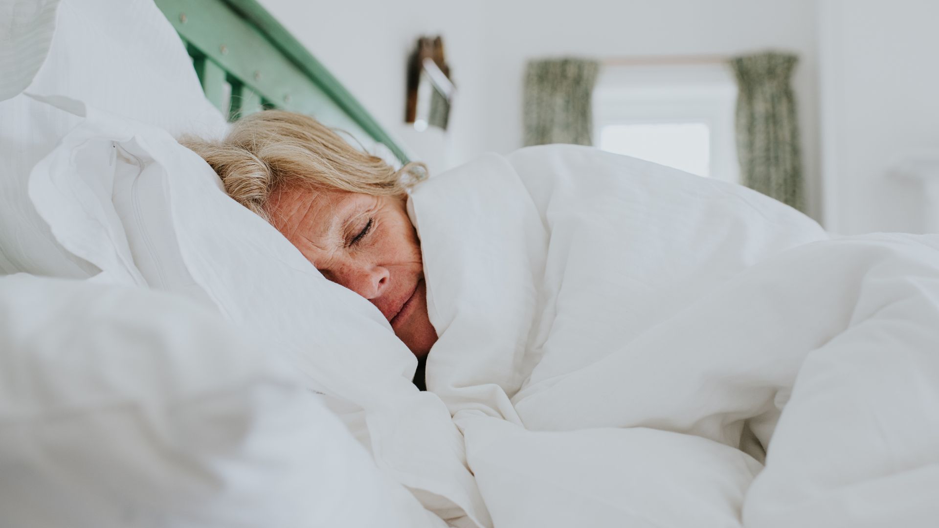 A woman wrapped in a thick, white duvet in bed