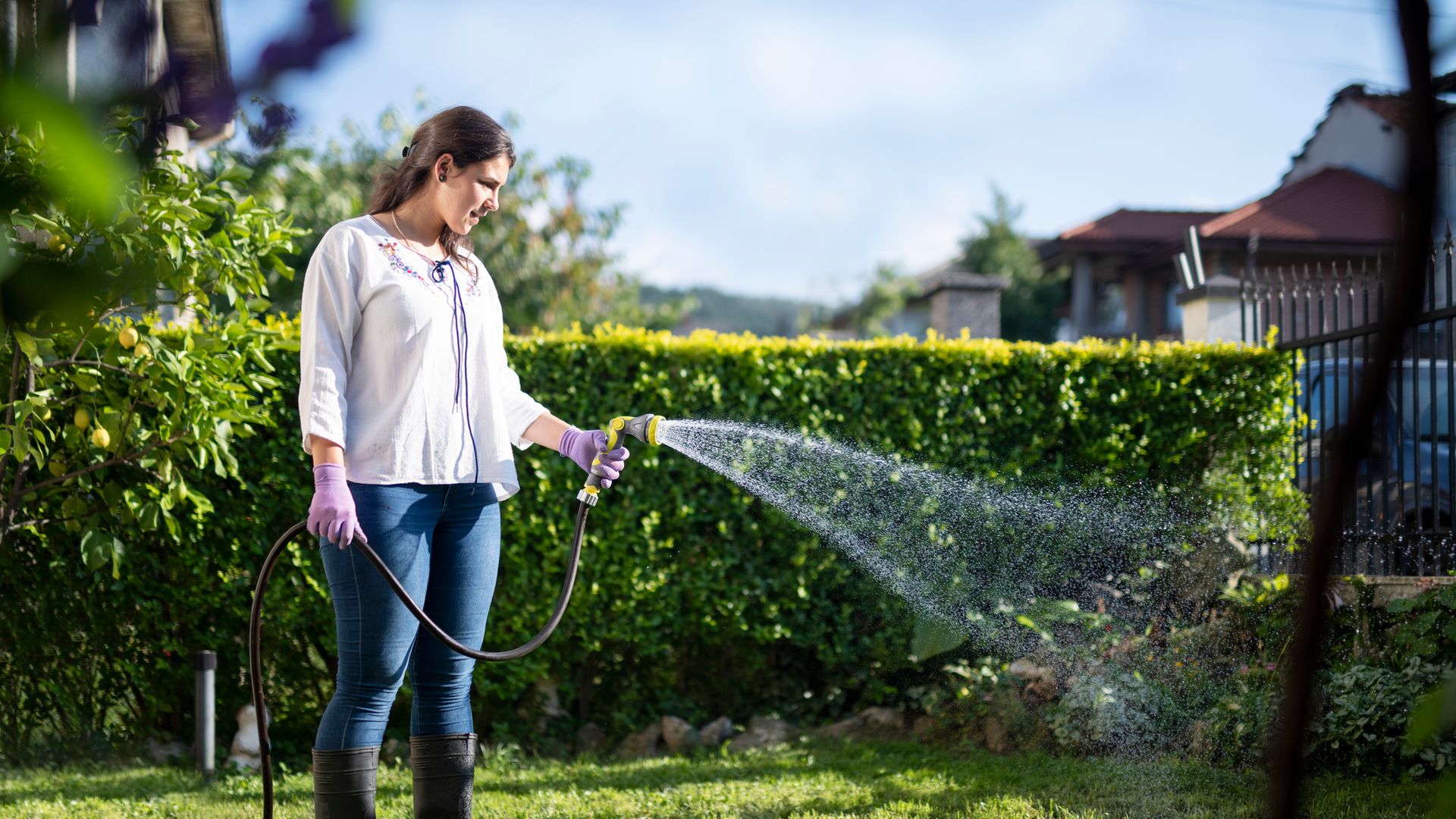 woman watering garden with hose