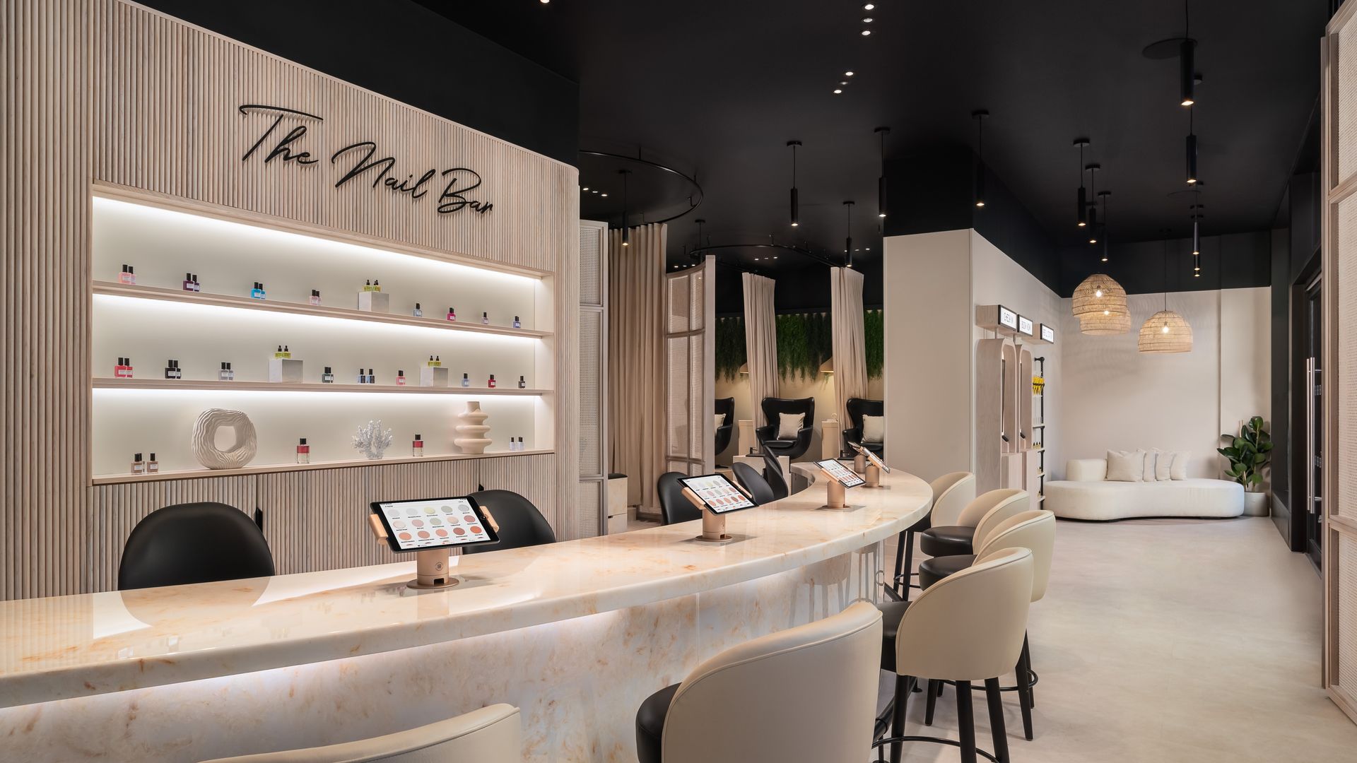 Marble bar with white chairs and iPads to select nail shades