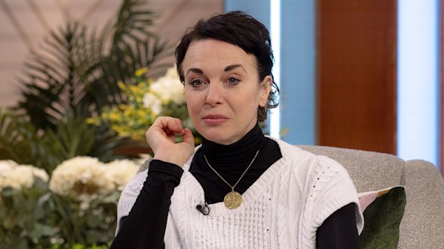 Amanda Abbington looking sad in a white cardigan and black turtleneck