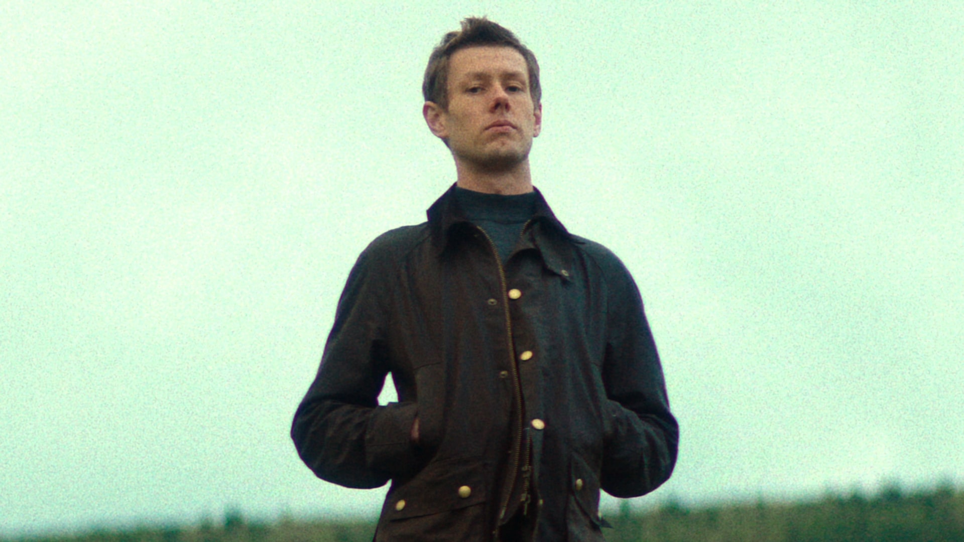 man standing on hill with hands in pockets