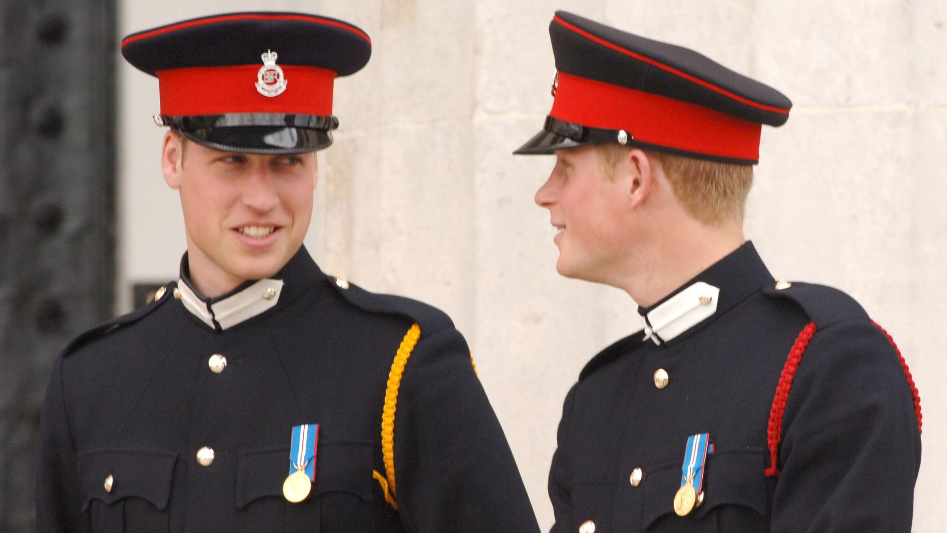 Prince William smiling at Prince Harry in military uniform