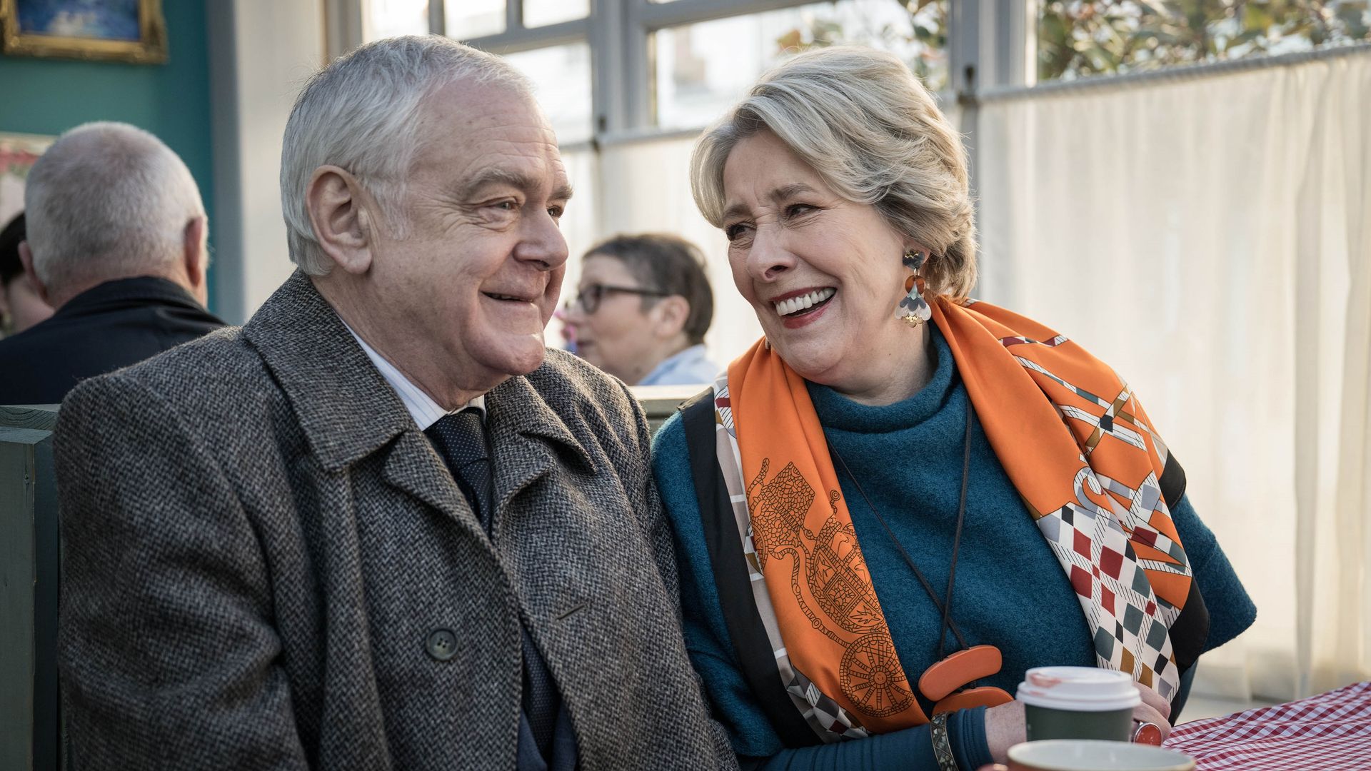 man and woman laughing sitting at cafe