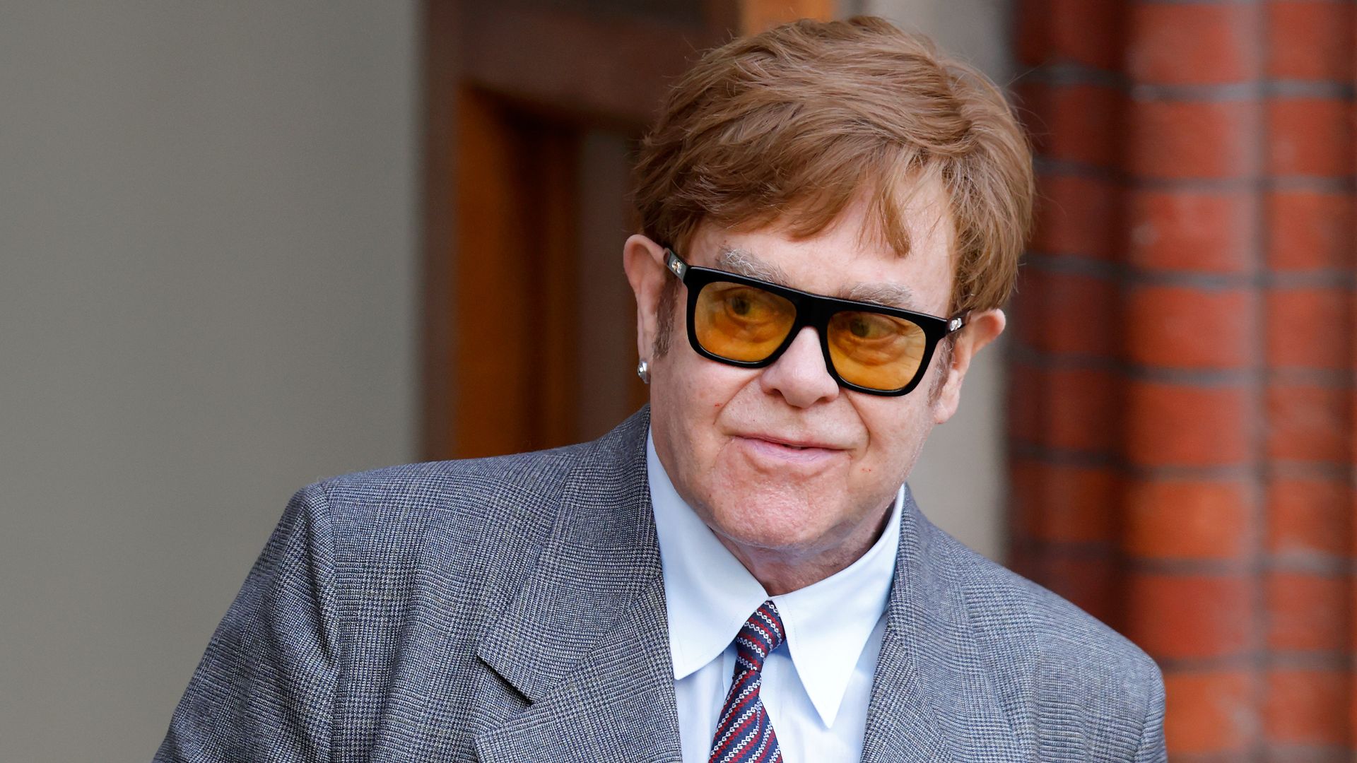 Elton John in a light grey suit