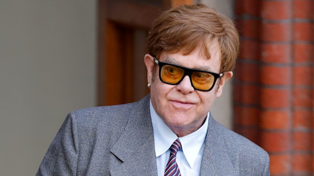 Elton John in a light grey suit