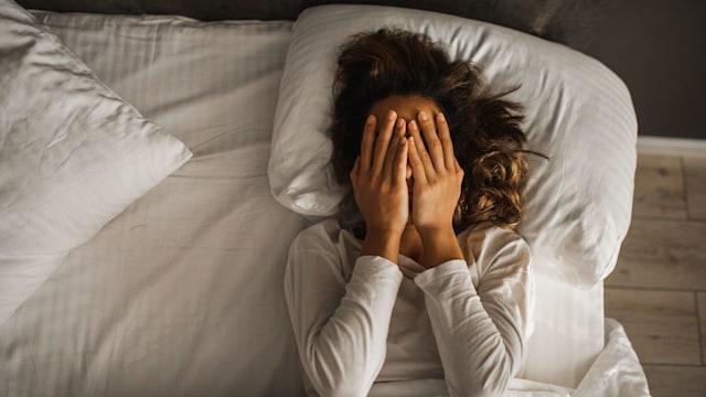 Tired woman in bed with hand over face