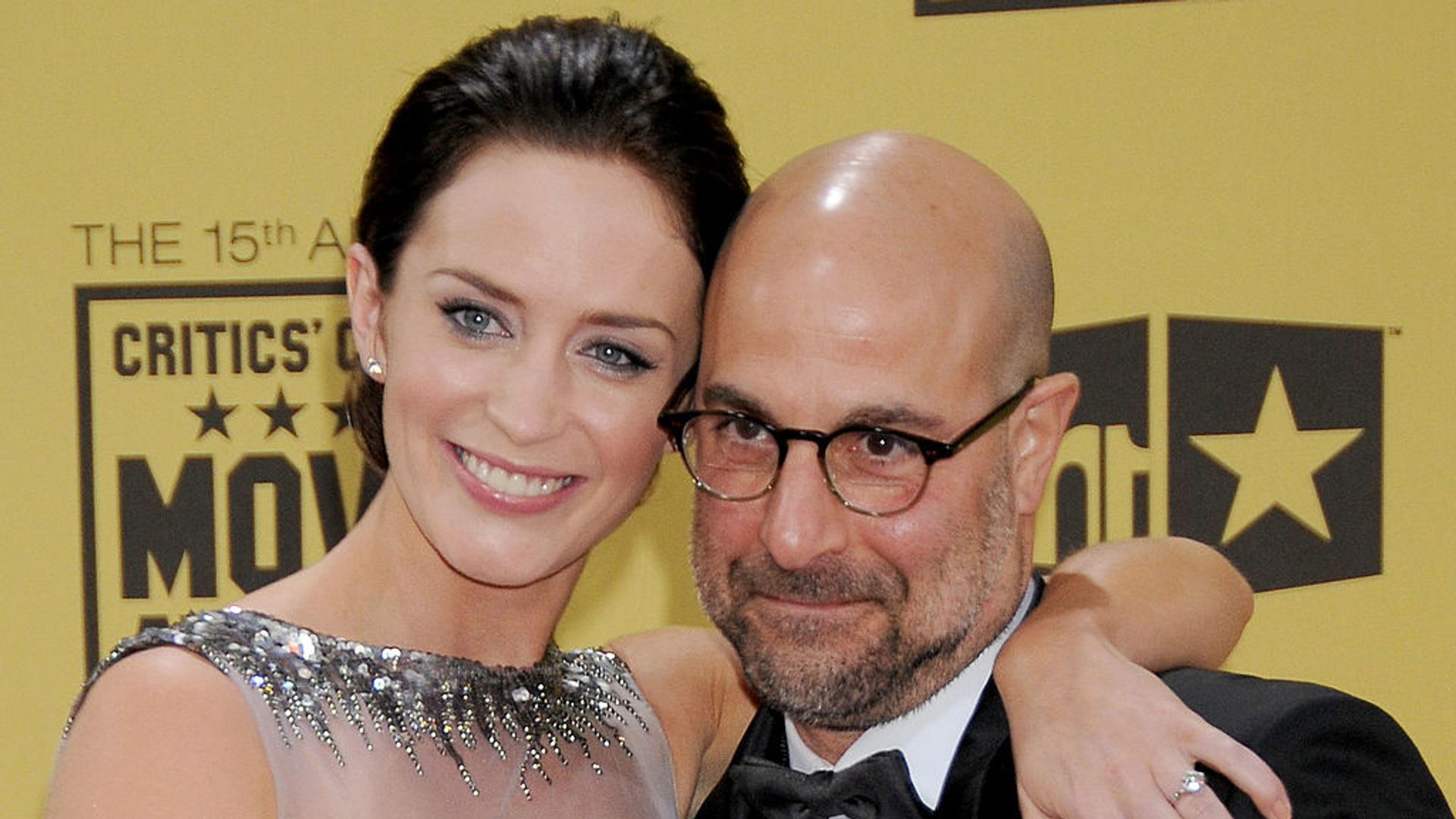 Emily Blunt wearing a high neck sequin gown as she cuddles her co-star Stanley Tucci