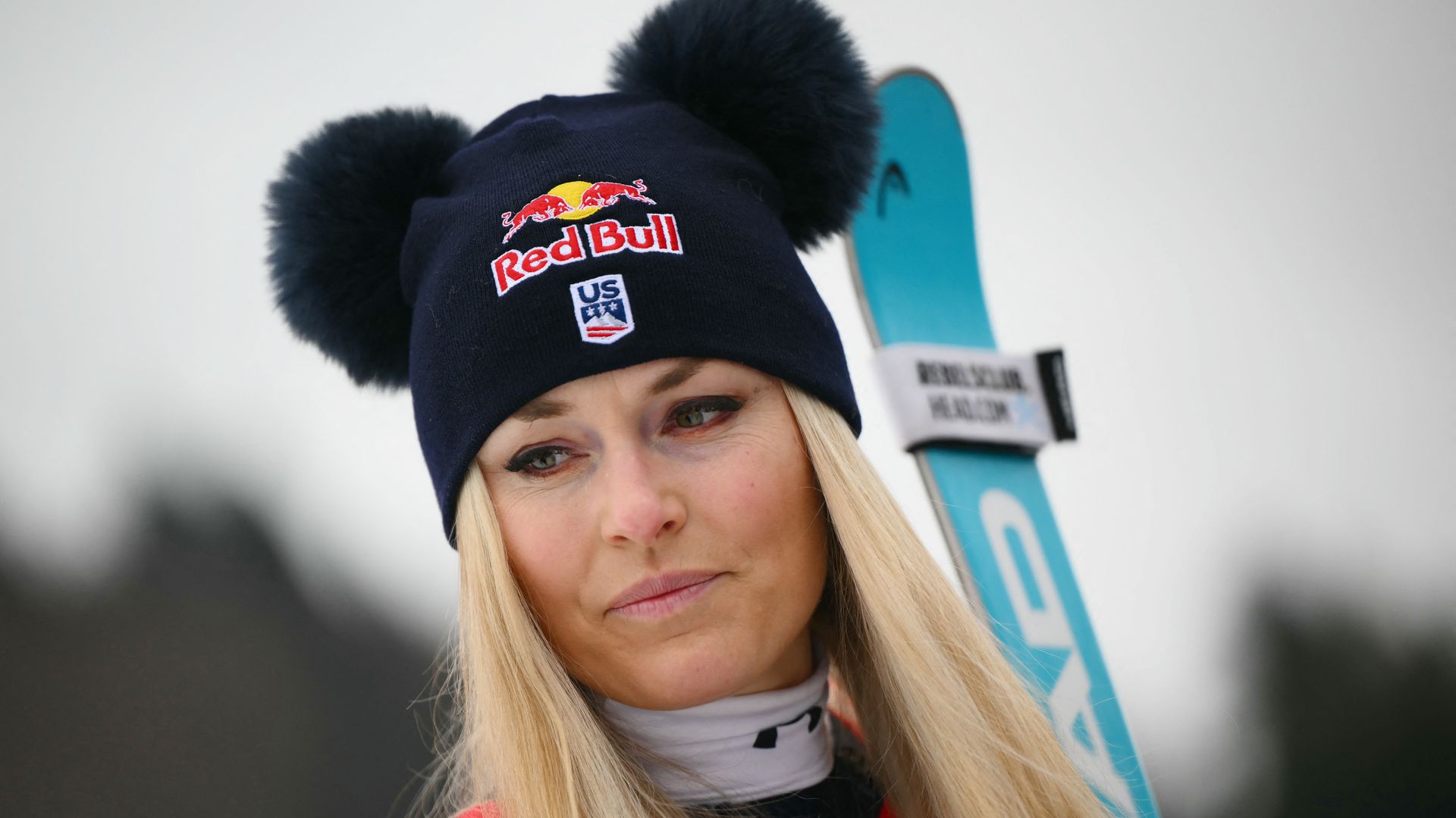 Lindsey Vonn  looking sad, wool hat carrying skis