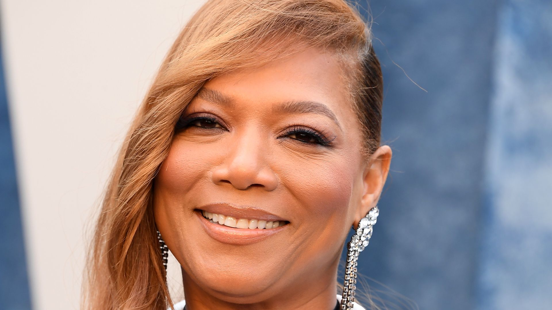 Queen Latifah wearing a heart necklace and a monochrome jacket