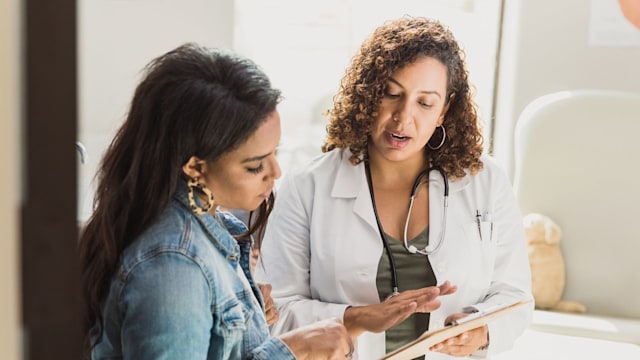 A female doctor discusses a young patient's diagnosis with the patient's mother. They are reviewing the patient's test resutls.