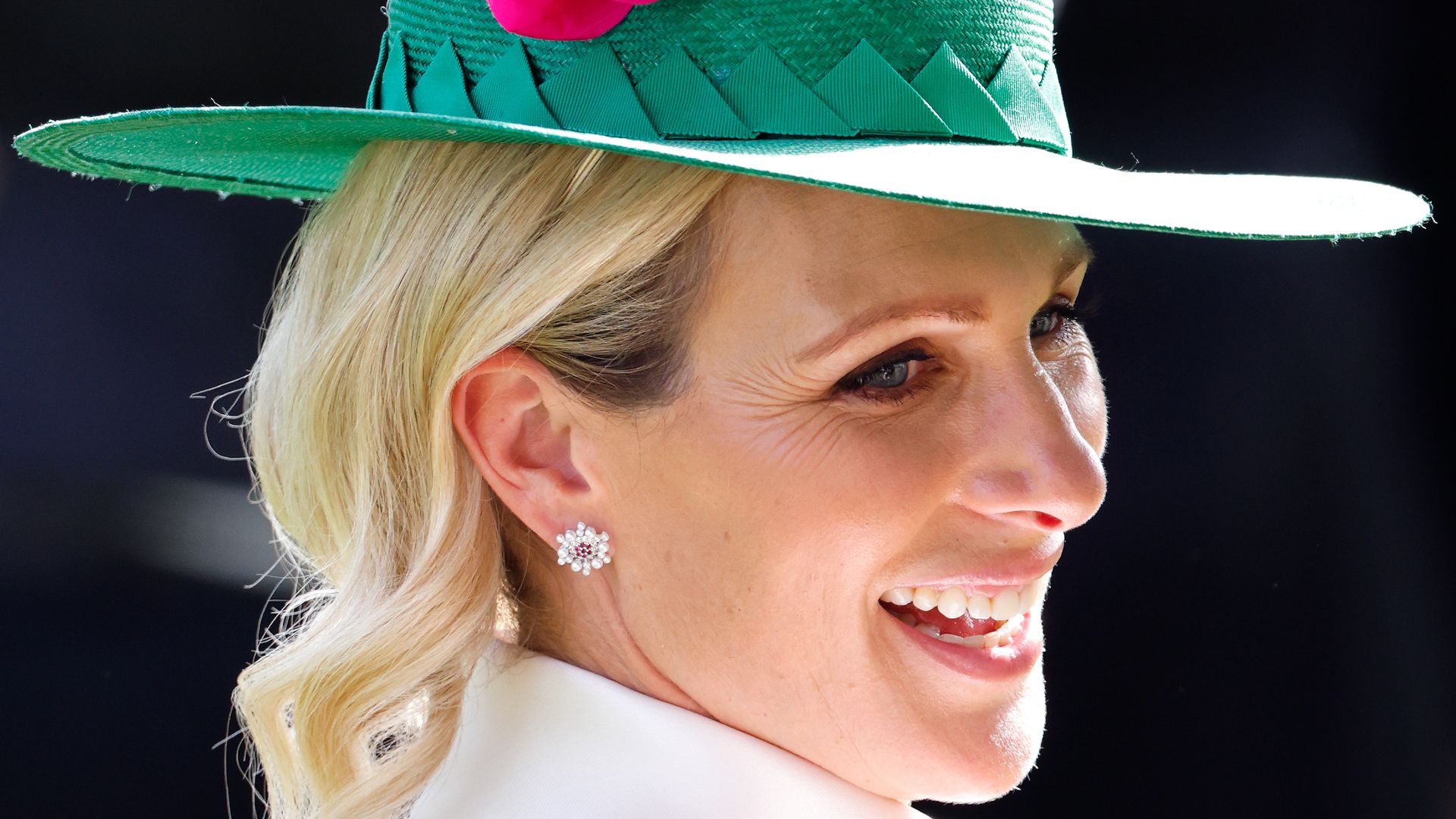 Zara Tindall smiling at Royal Ascot wearing a green and pink hat