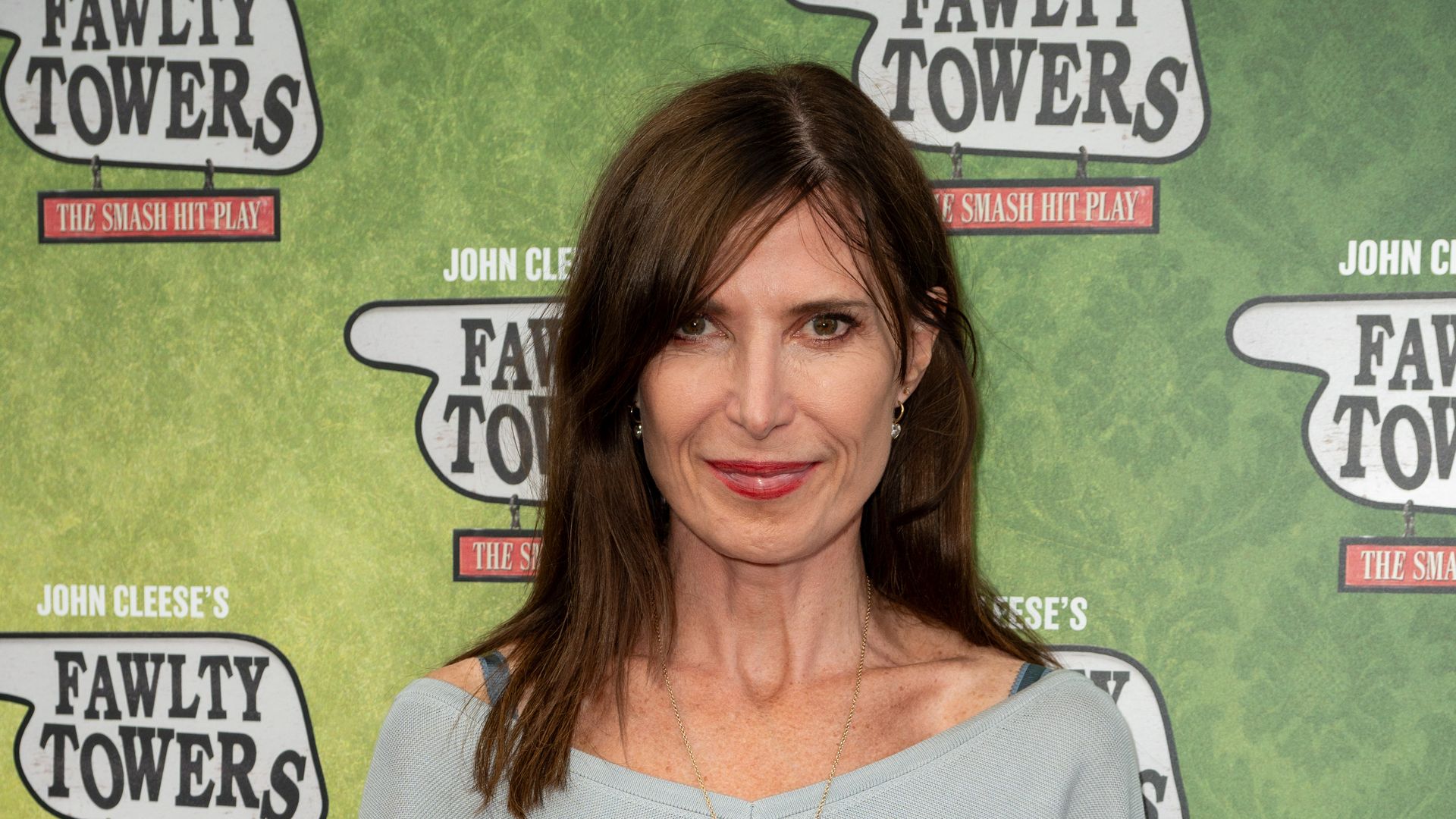 Ronni Ancona smiling in an off the shoulder top and white skirt