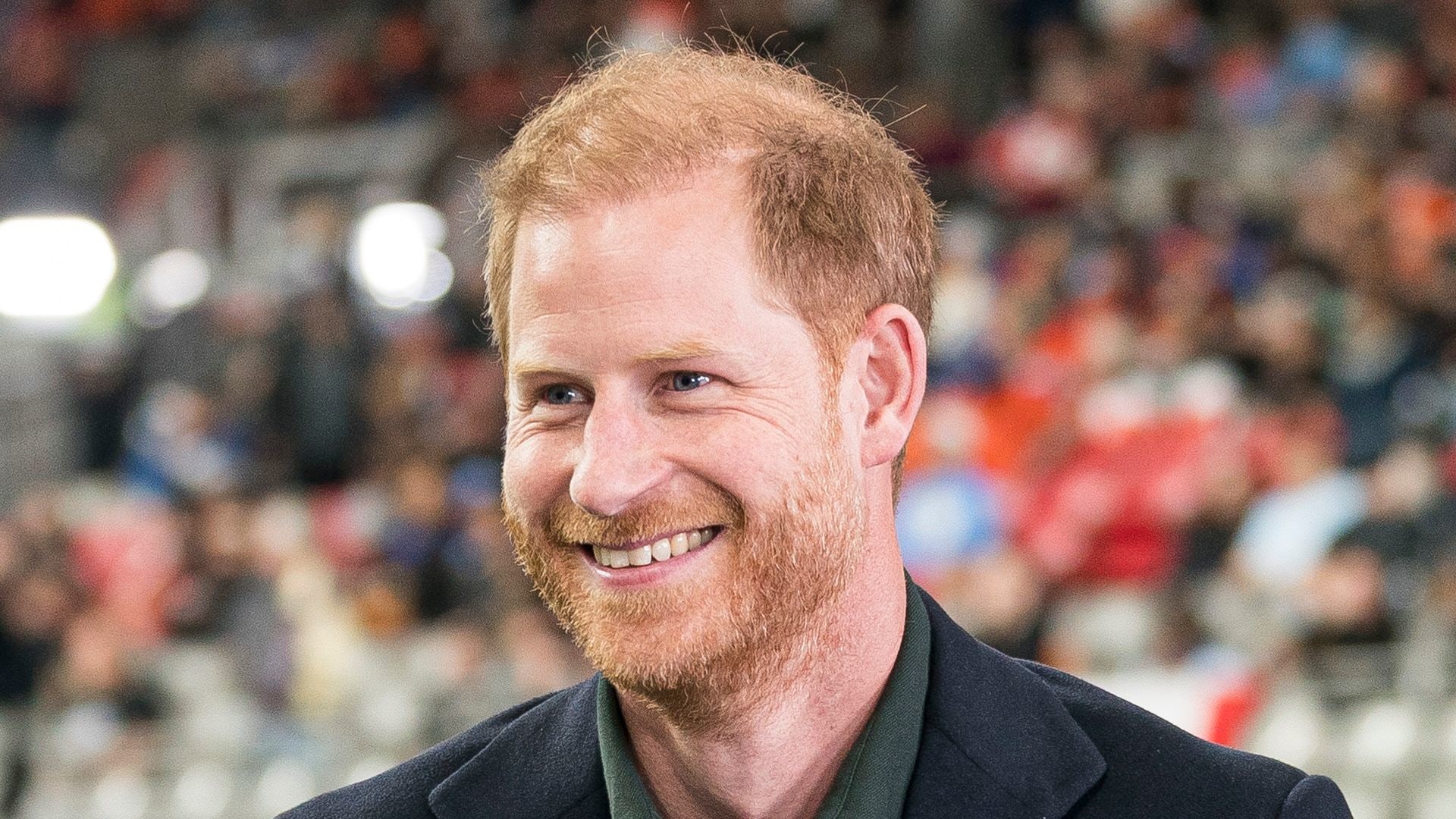 Prince Harry smiling in stadium holding mic