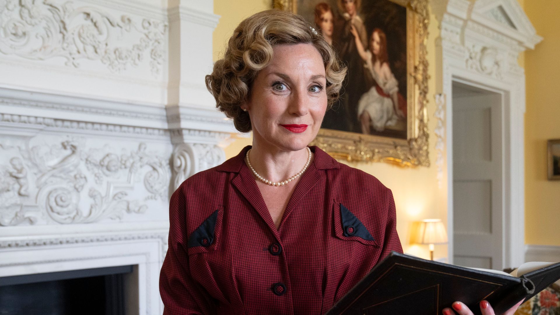 Woman in red dress and curled hair holding book 