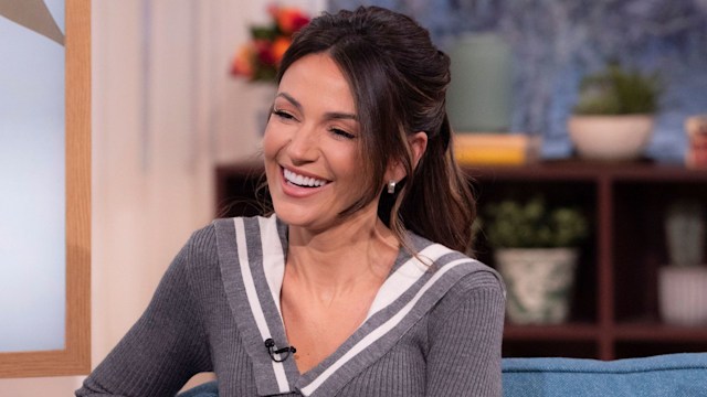 Brunette women in grey jumper sitting on blue sofa in TV studio