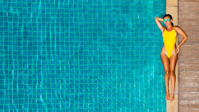 Woman wearing yellow swimsuit by swimming pool