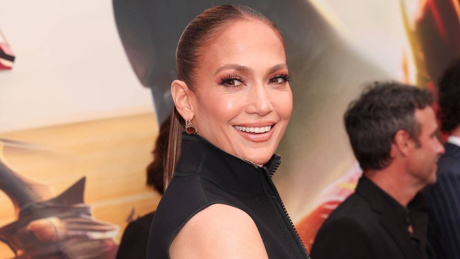 Jennifer Lopez smiling with her head turned over her shoulder at a red carpet premiere