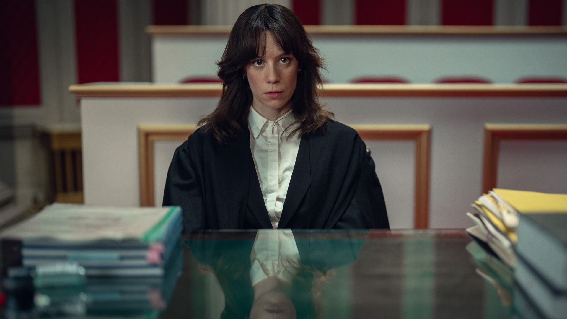 young brunette woman in white shirt and black robe sitting at desk