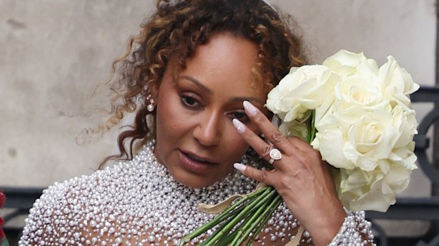 Mel B pushing hair off her face holding her bridal bouquet