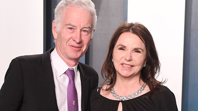 John McEnroe in a black suit and Patty Smyth in a black jumpsuit