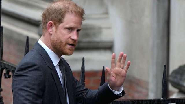 Prince Harry waves to the media as he arrives at the Royal Courts Of Justice in London