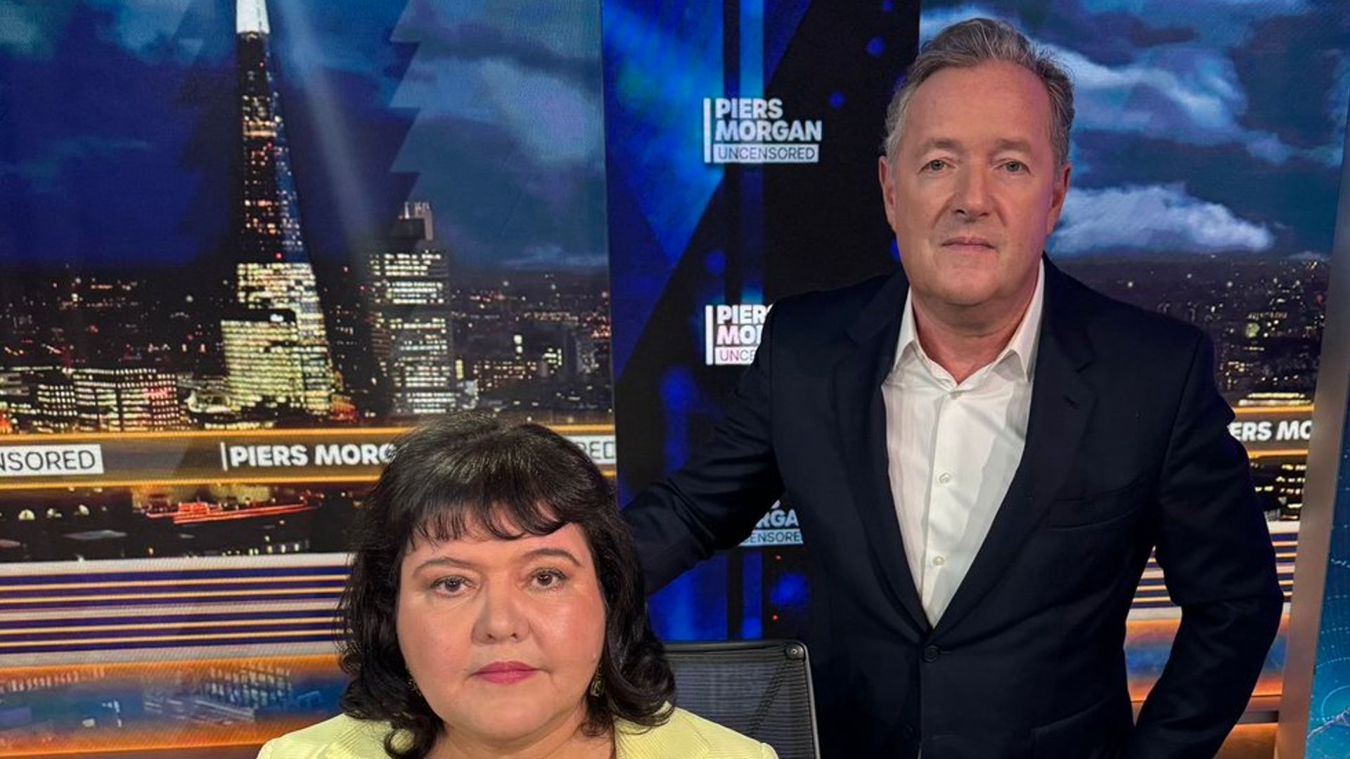 Piers Morgan next to Fiona Harvey, who is sitting in a chair