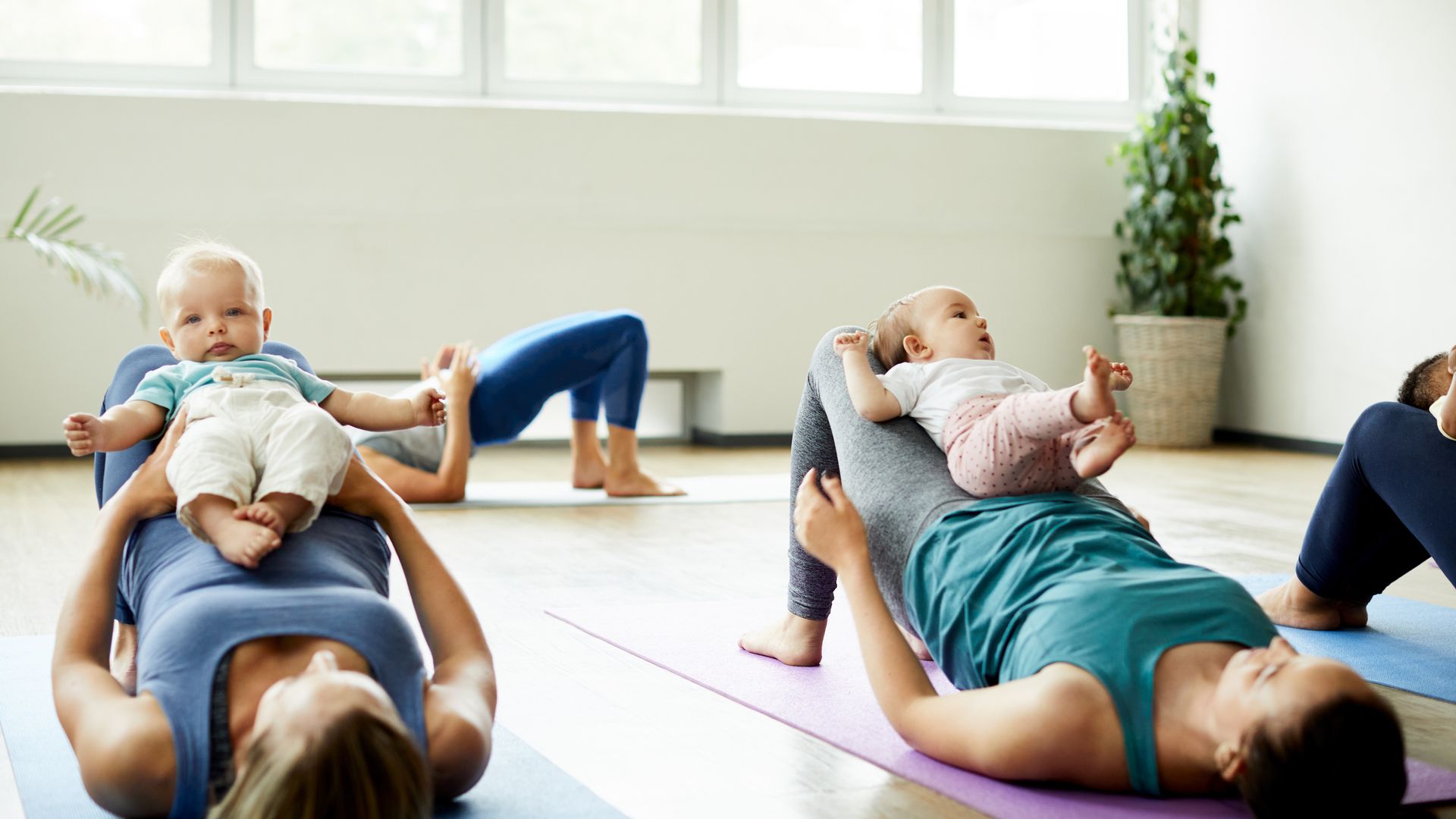 Cropped shot of a young group of mothers lying down and posing with her babies during a baby yoga class