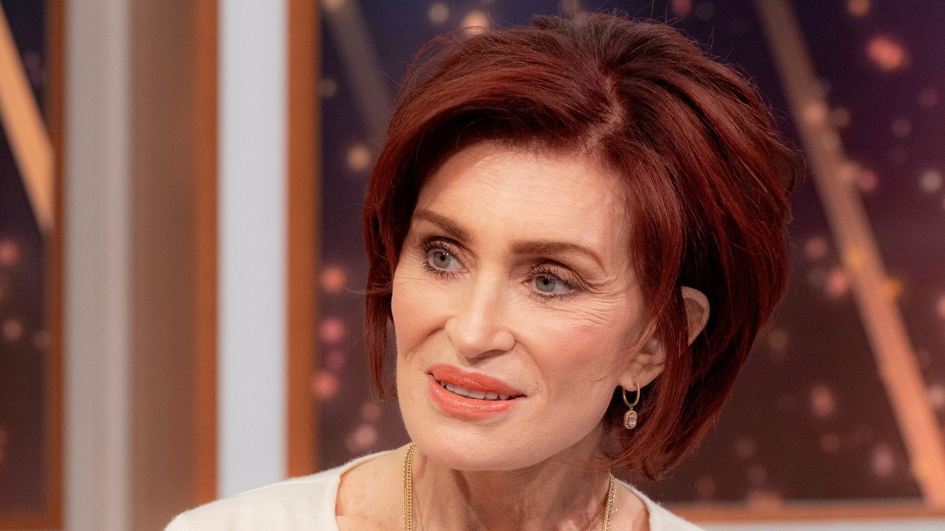 Sharon Osbourne in a white dress and gold necklace