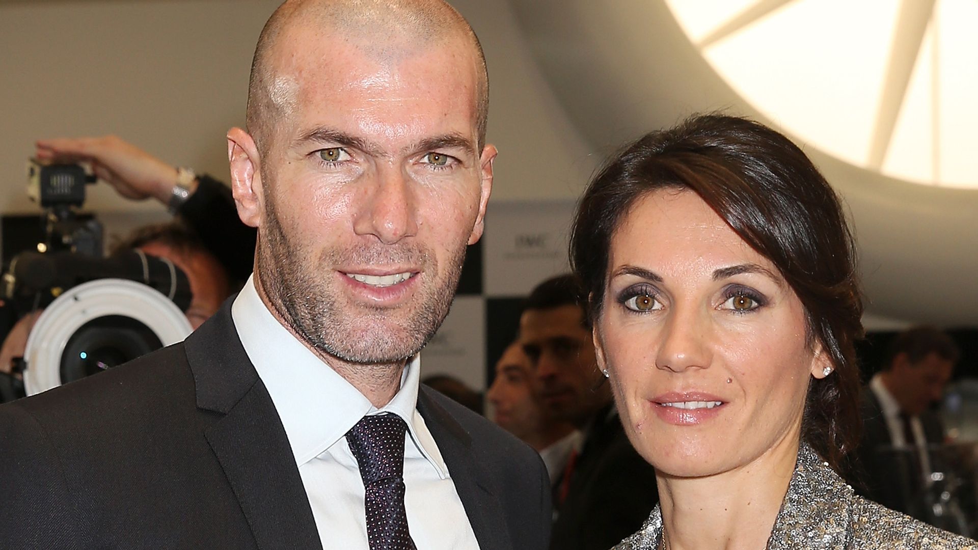 Zinedine Zidane in a suit and Veronique Zidane in a sparkly silver jacket