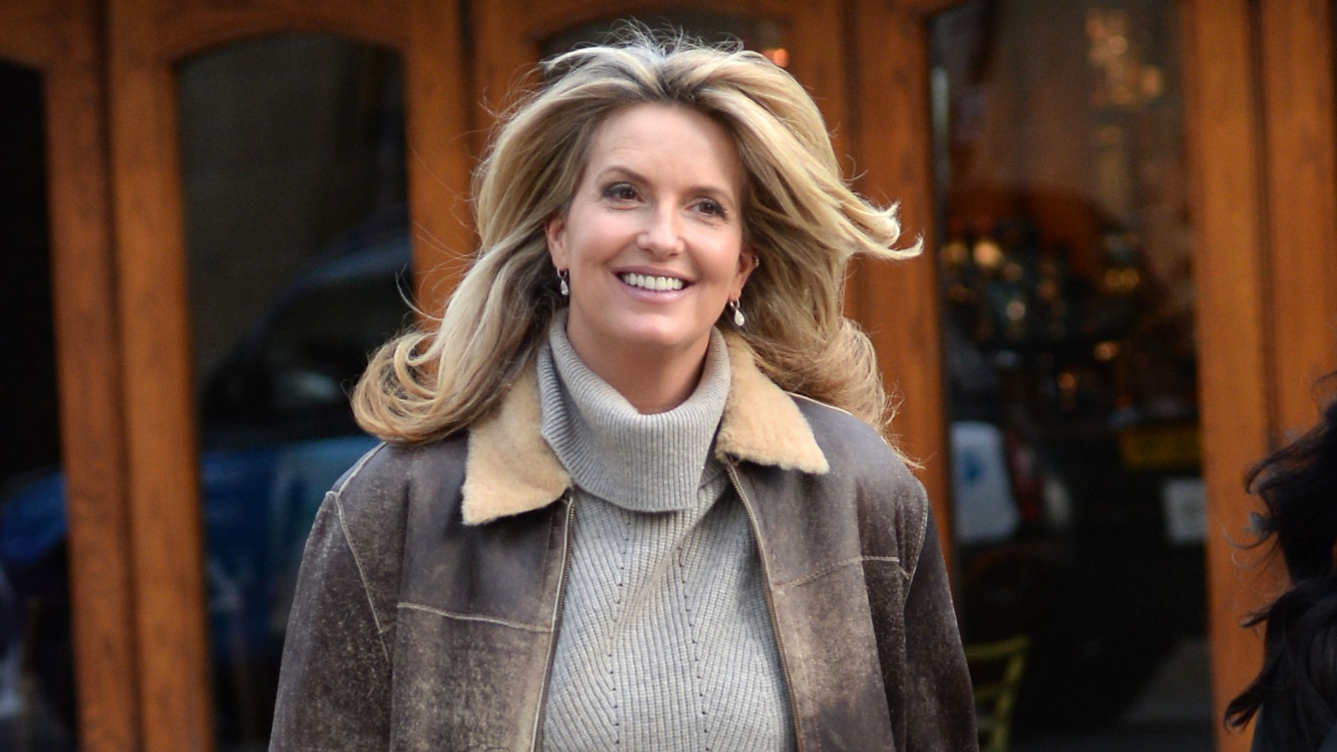 Penny Lancaster in brown coat and grey jumper