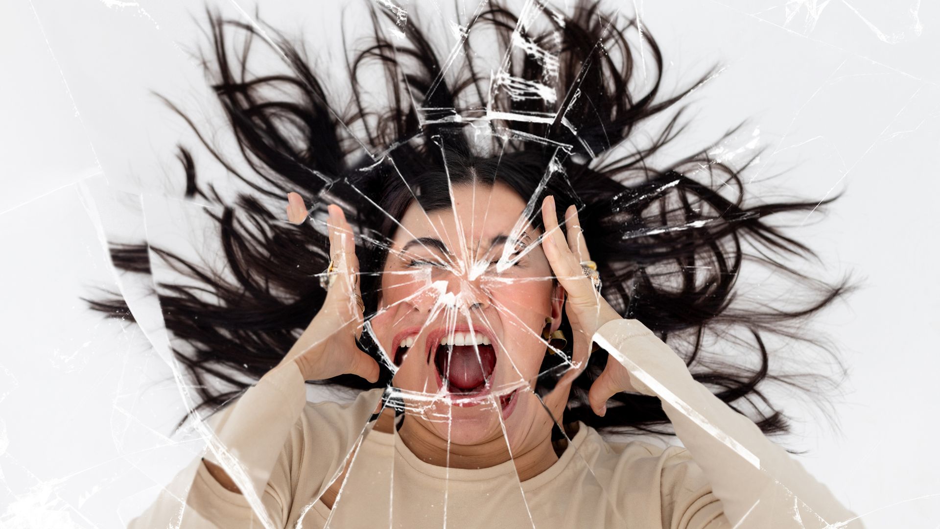Woman screaming with her hands either side of her head with a cracked mirror effect over the image.