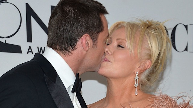 Hugh Jackman holding an award and kissing Deborra-Lee Furness in a feathered dress