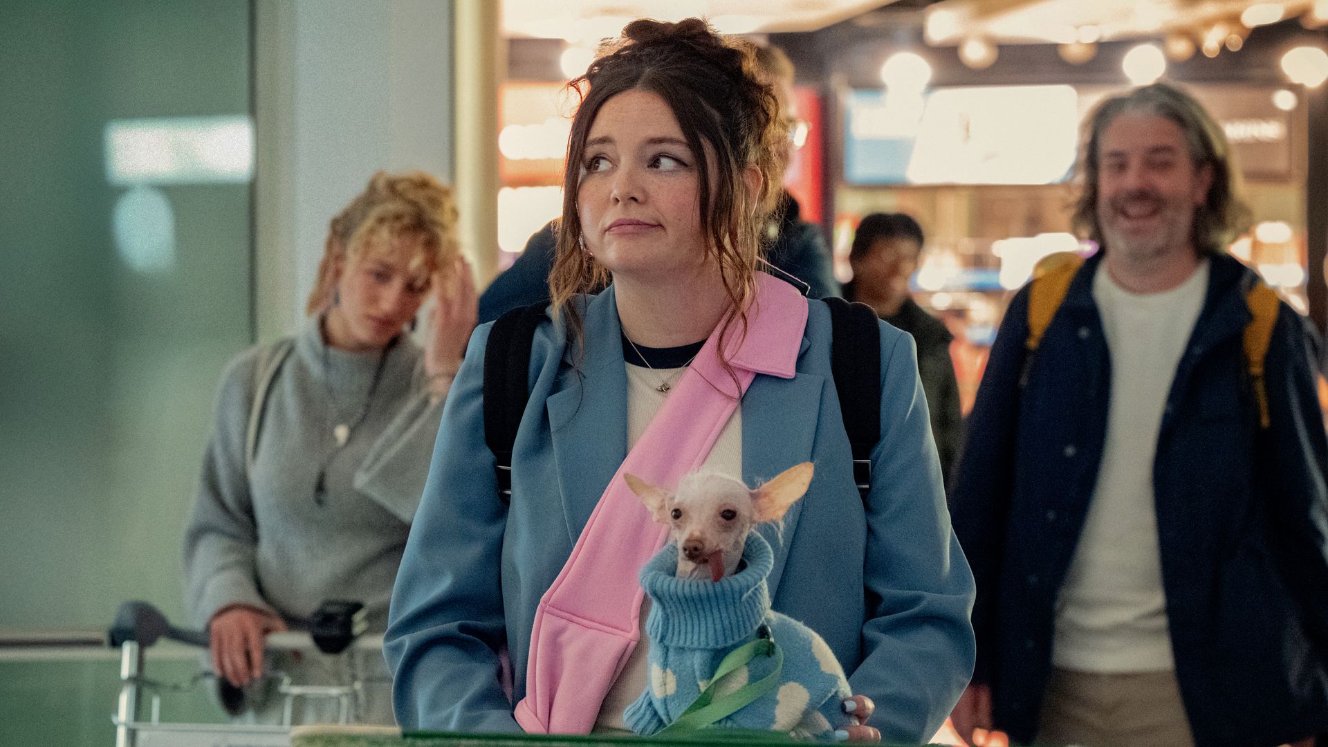 woman pushing suitcase trolley with small dog on topthrough airport