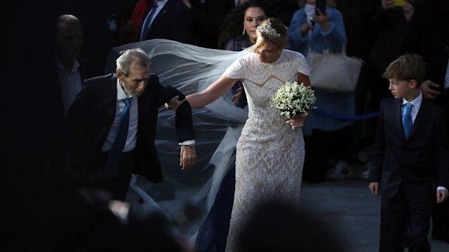 Chrysi Vardinogianni (C) is accompanied by her father Giorgos Vardinogianni (L) as they arrive for her wedding with Nikolaos De Grece at the Church of Agios Nikolaos Rangavas in Athens