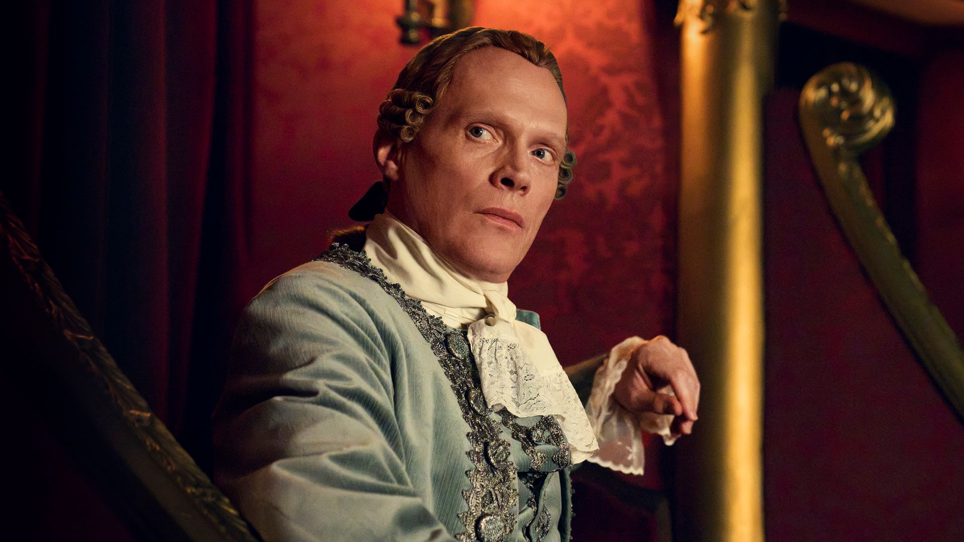 man in period clothing sitting in theatre seat