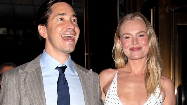 Justin Long in a suit with his arm around wife Kate Bosworth in a white dress