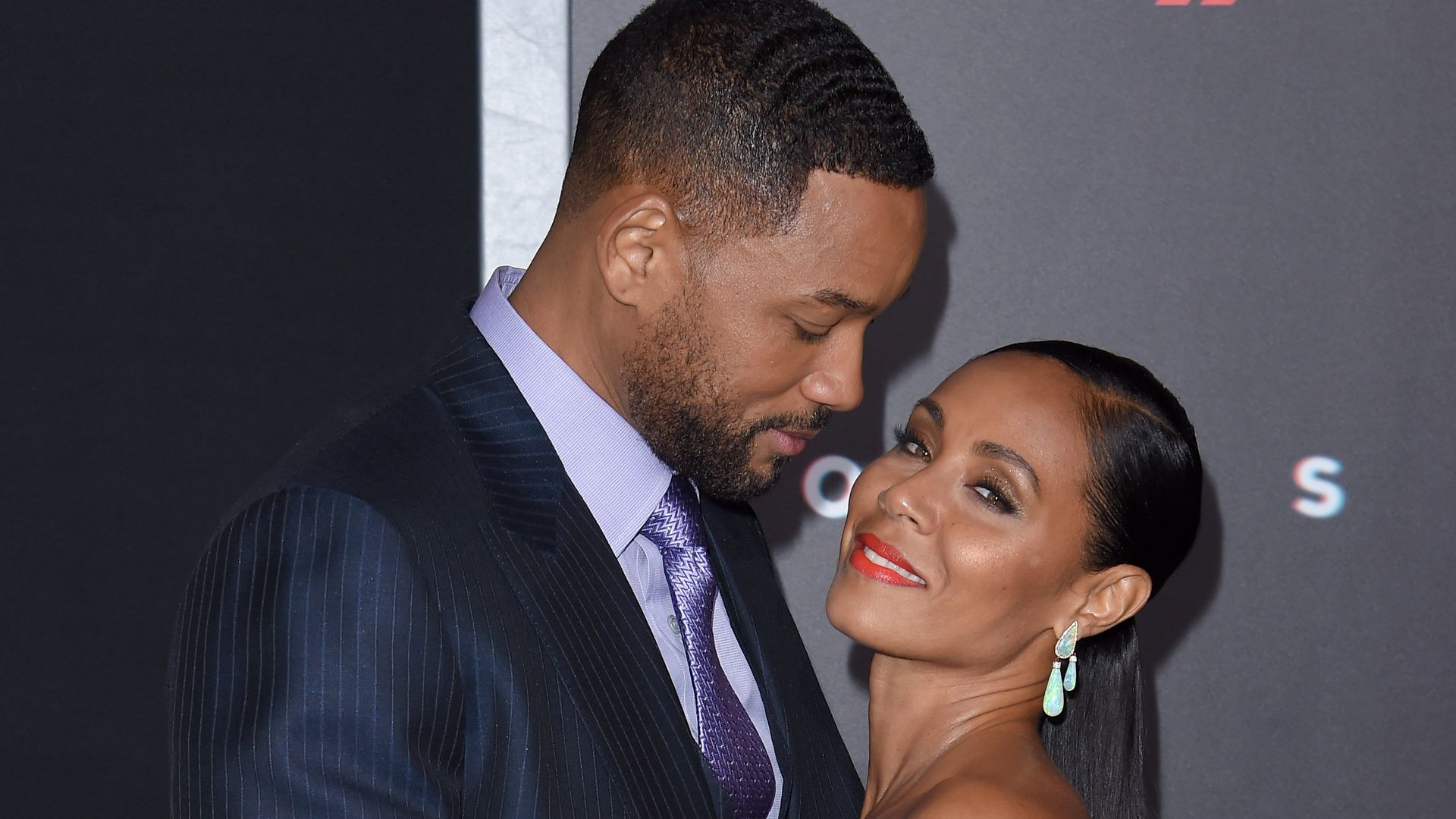 Will Smith and Jada Pinkett Smith smiling at each other while being photographed at a red carpet event