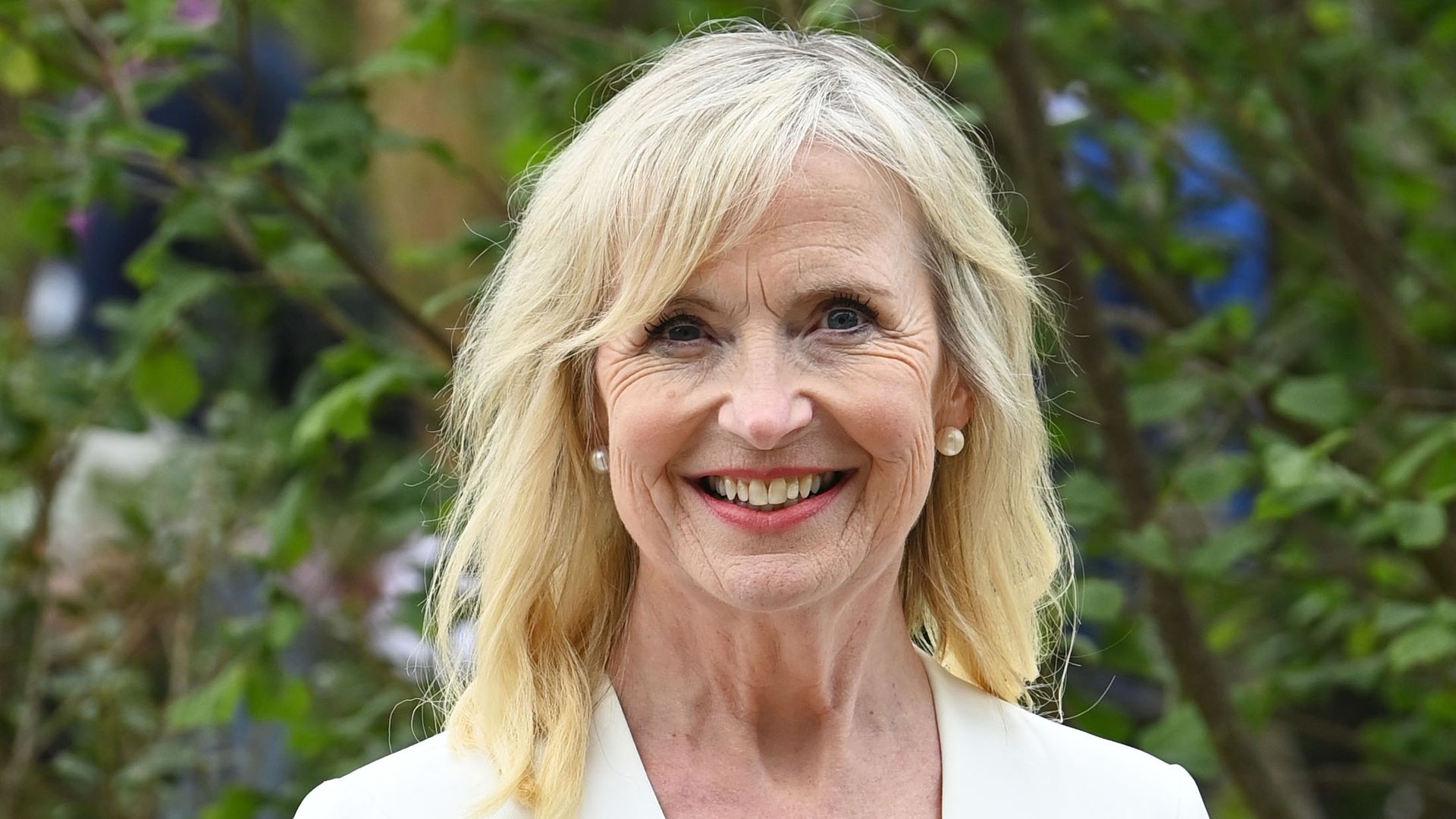 Carol Kirkwood posed outside in white dress