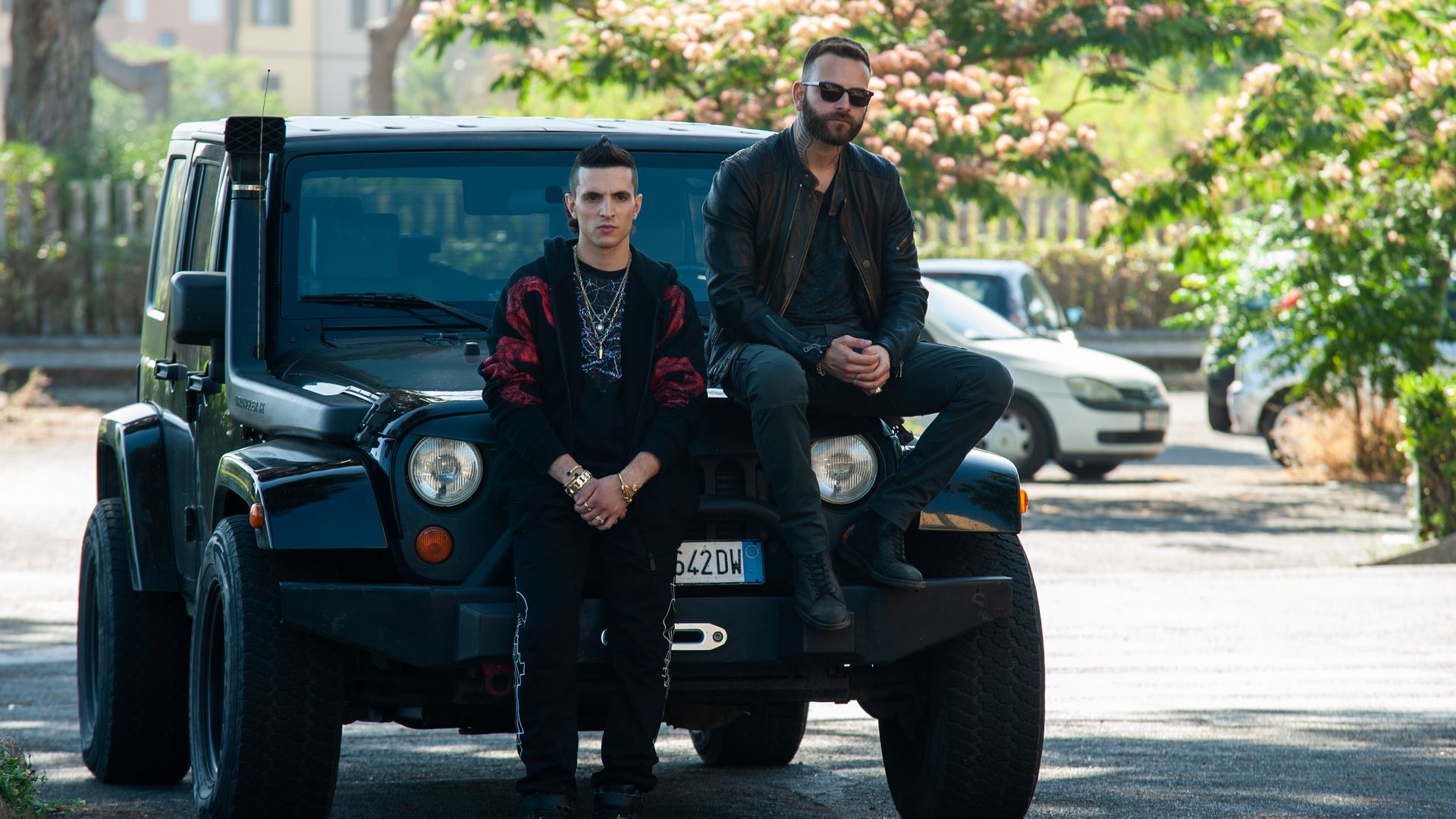 Two characters from Suburra: Blood on Rome sitting on a place vehicle
