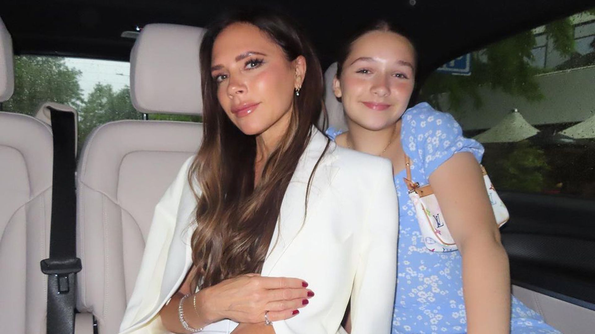Victoria and Harper Beckham pose for a photo in their car. 