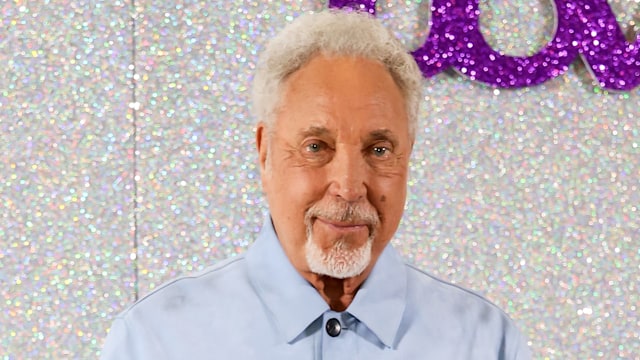 Sir Tom Jones in blue against glittery backdrop