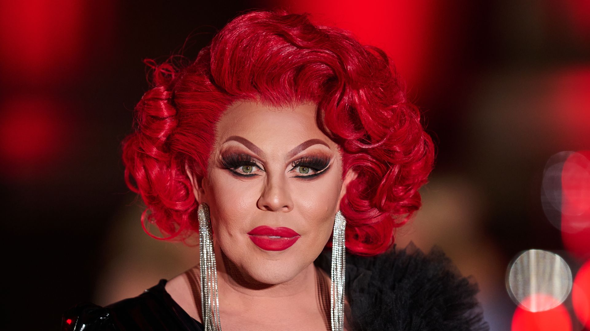 La Voix in a black dress with a red wig