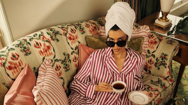 A model poses on a floral couch wearing a pair of striped pyjamas and a towel on her head