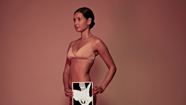 Female holding tablet in front of body to display coloured x-ray illustrations made out of hand made paper structures