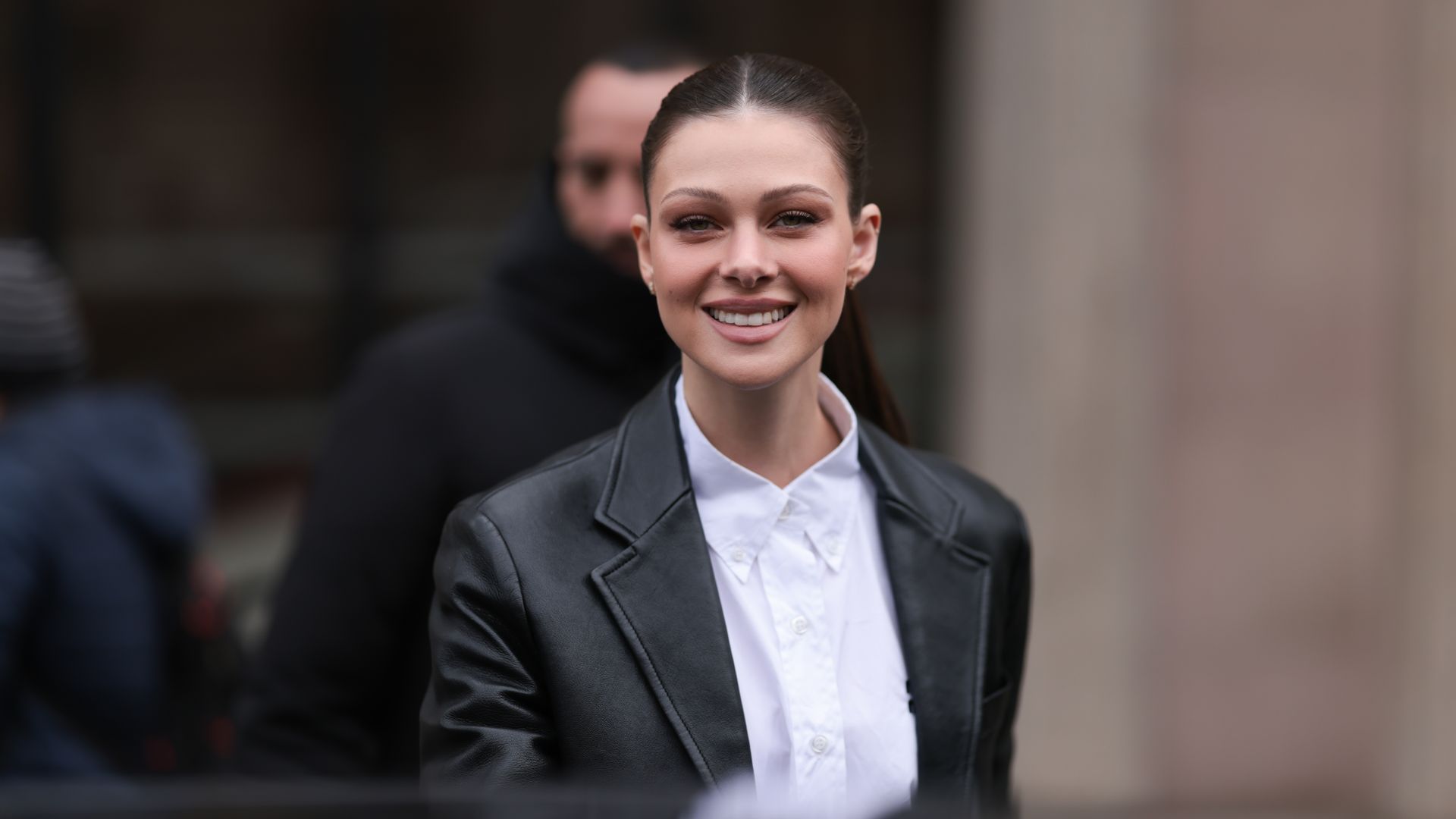Nicola Peltz seen wearing a black leather jacket and a white blouse before the Miu Miu show 