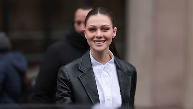 Nicola Peltz seen wearing a black leather jacket and a white blouse before the Miu Miu show 