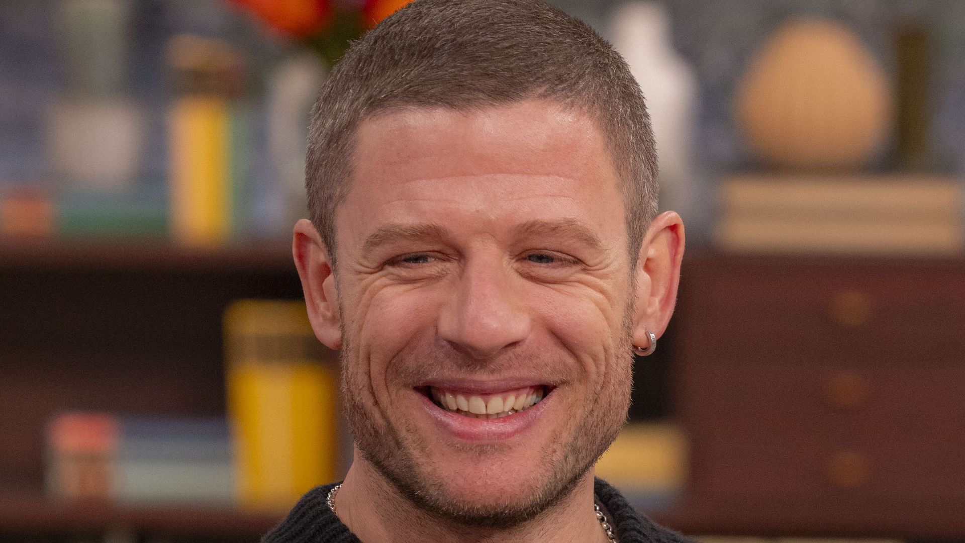 James Norton with a buzzcut in a knitted jumper