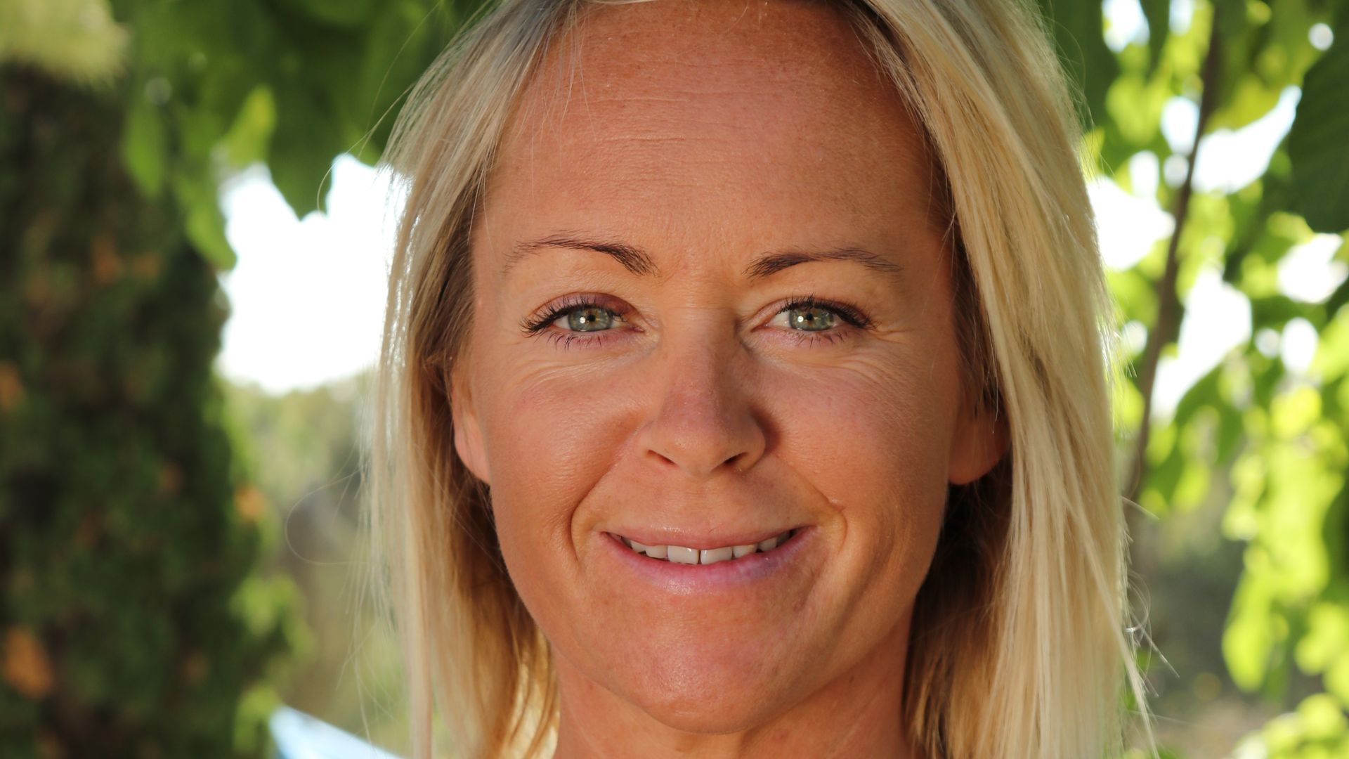 blonde woman smiling in a tank top