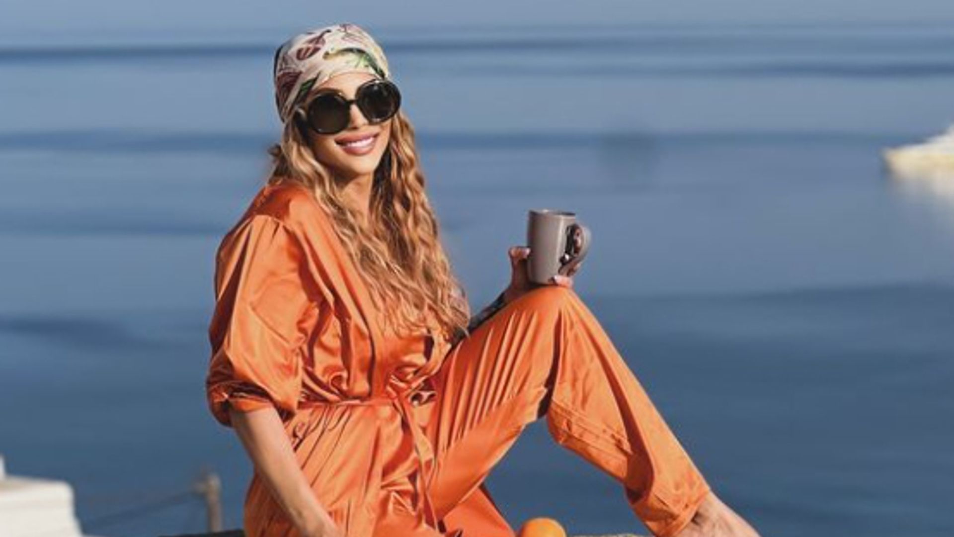 Farah El Kadhi in orange outfit posing on a building